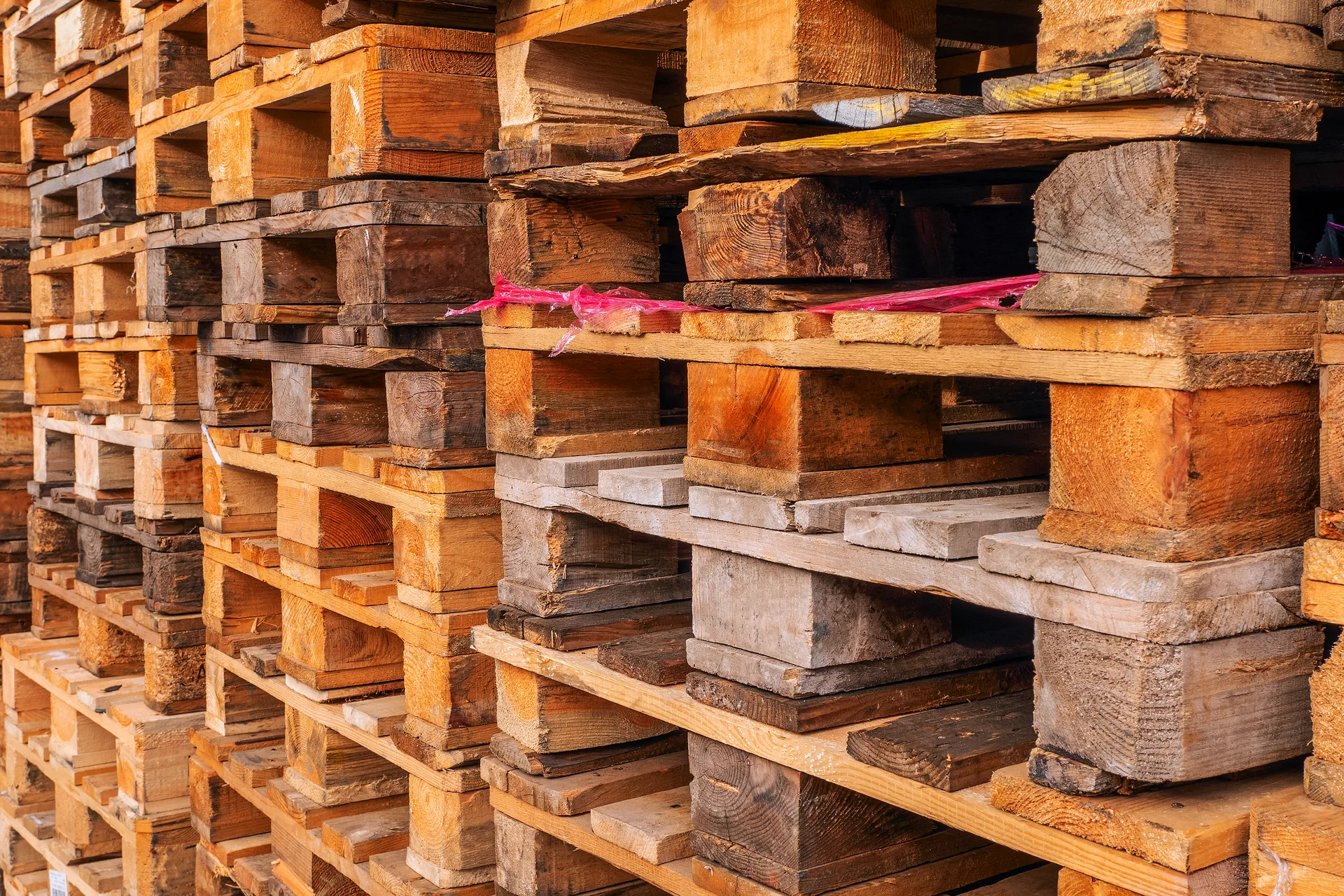Close view of stacked used wooden pallets showing varied blocks, boards and signs of previous use
